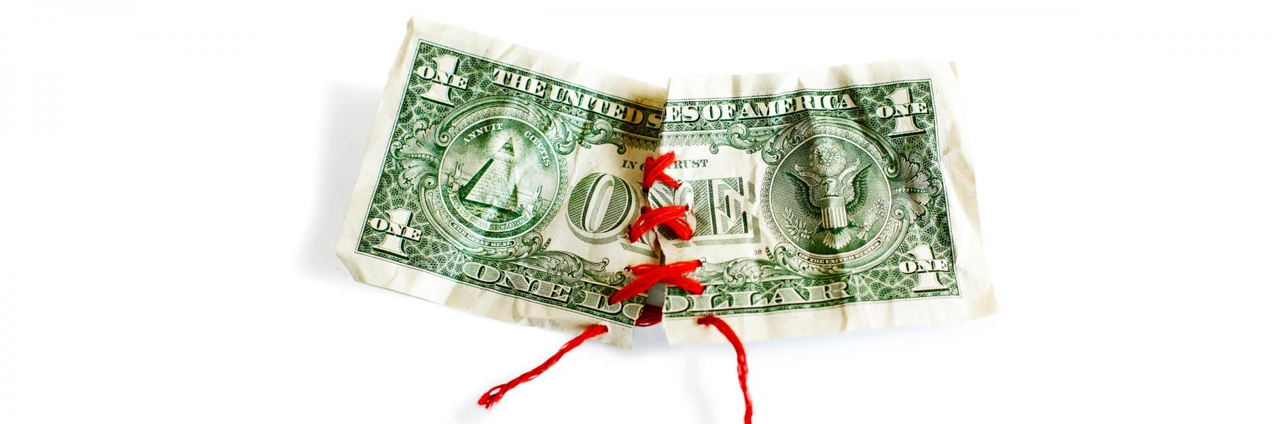 torn dollar bill sewn back together with red thread