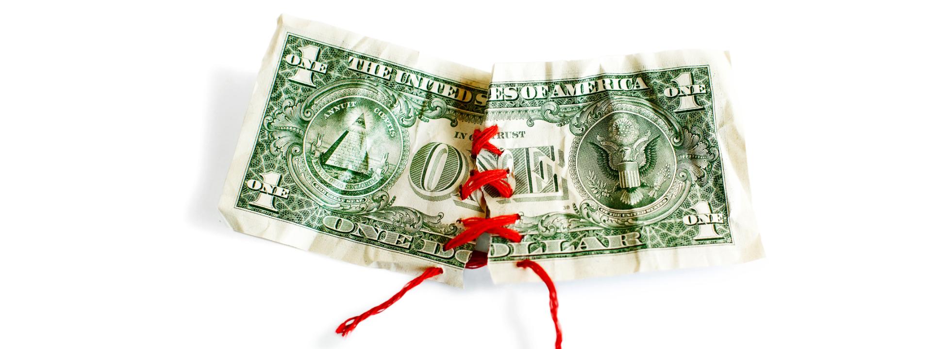 torn dollar bill sewn back together with red thread