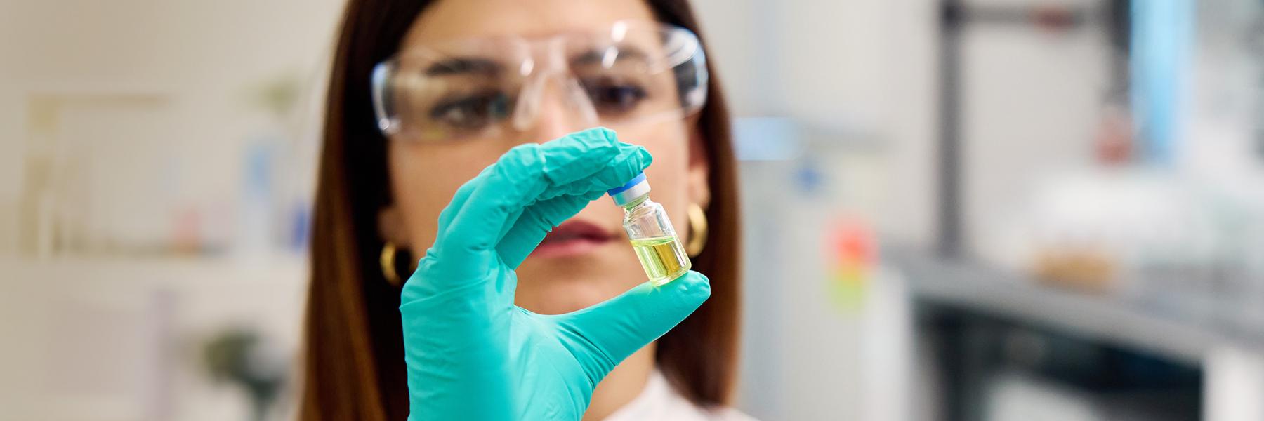 lab researcher holds in her gloved hand a vial of the HIV drug lenacapavir