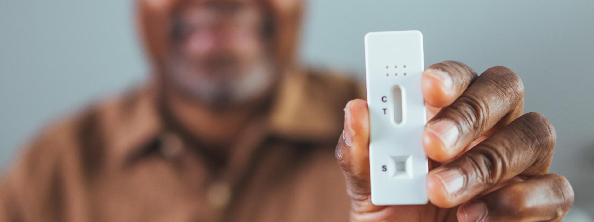 man holding up an at-home COVID-19 test