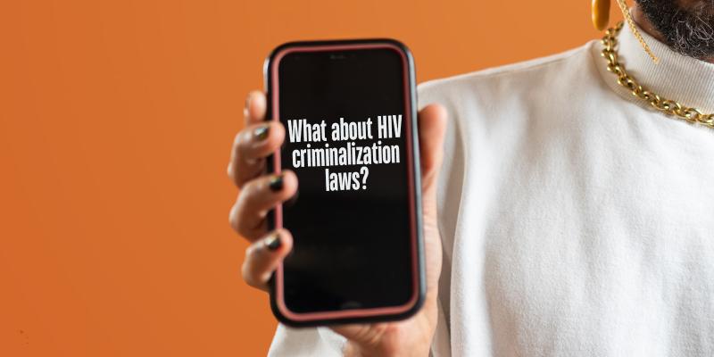 Bearded person holding iPhone with text on the screen: “What about HIV criminalization laws?”