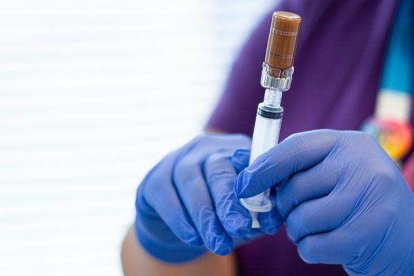 image of medical profession using a heavy gauge syringe to draw medication from a vial