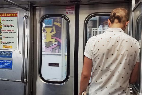 Young male aboard Chicago commuter train in front of public service ad for PrEP