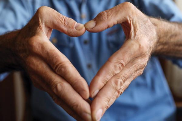 the shape of a heart, formed by the hands of an elderly man
