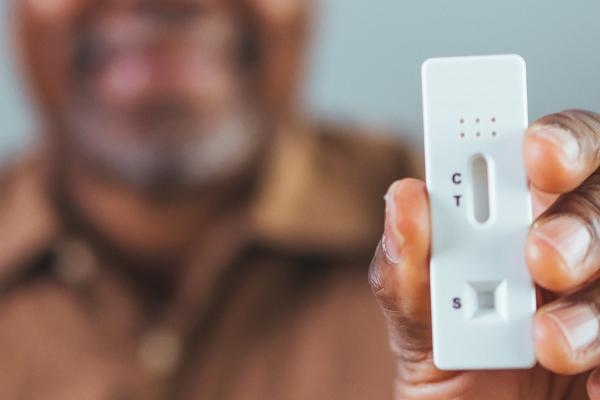 man holding up an at-home COVID-19 test