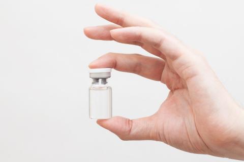 doctor's hand holding a medical vial