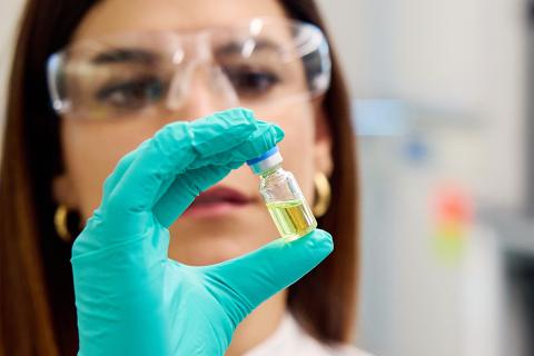 lab researcher holds in her gloved hand a vial of the HIV drug lenacapavir